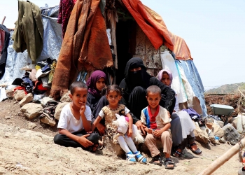 A displaced mother and her 5 children sitting outside their tent