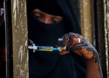 An EU-supported health worker prepares a vaccination shot at a mobile health clinic in a camp housing thousands of displaced Yemenis.