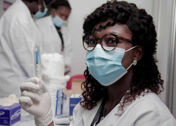 A nurse holding a syringe donated by COVAX